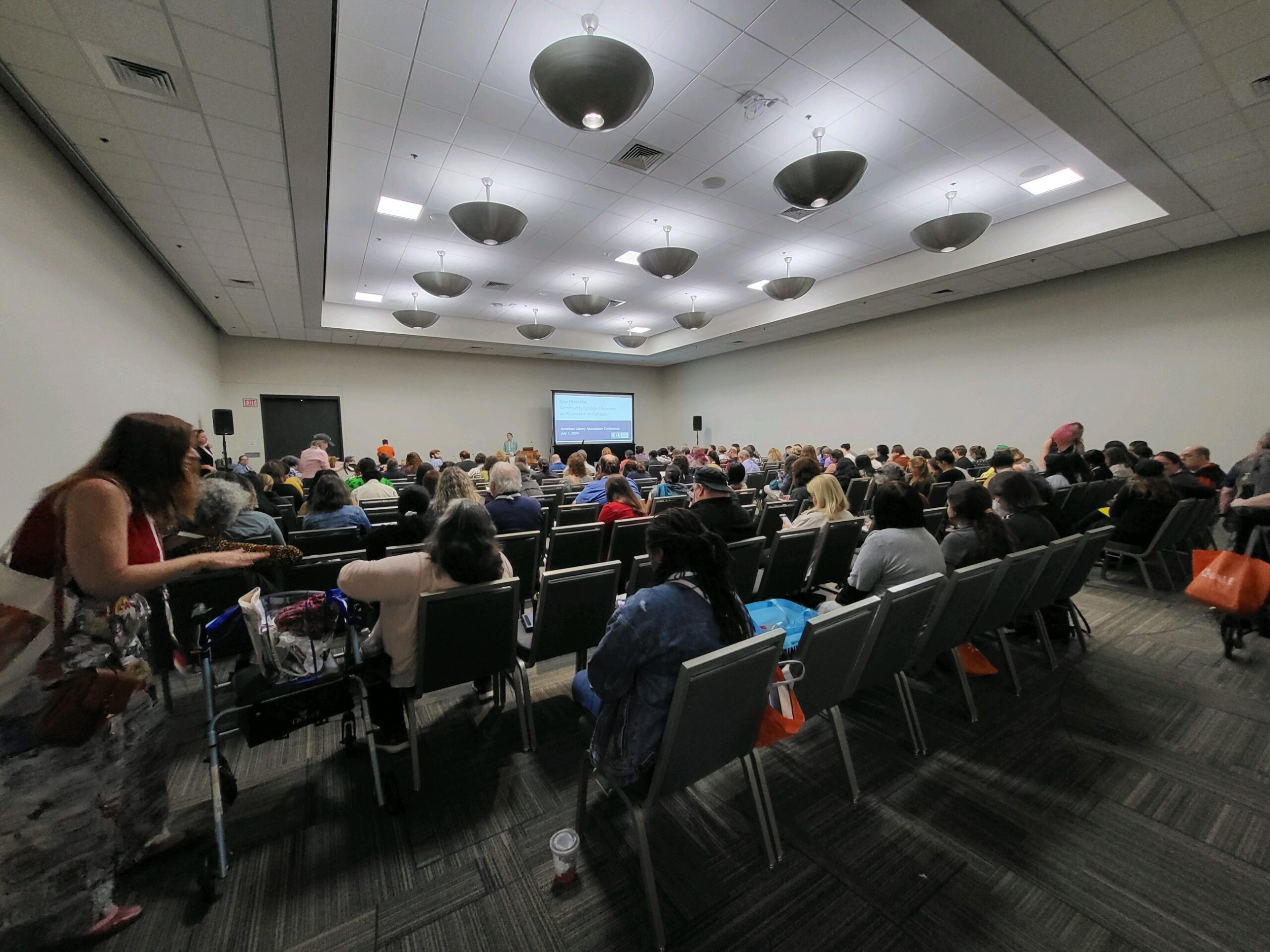 A filled room of people attending a conference session.