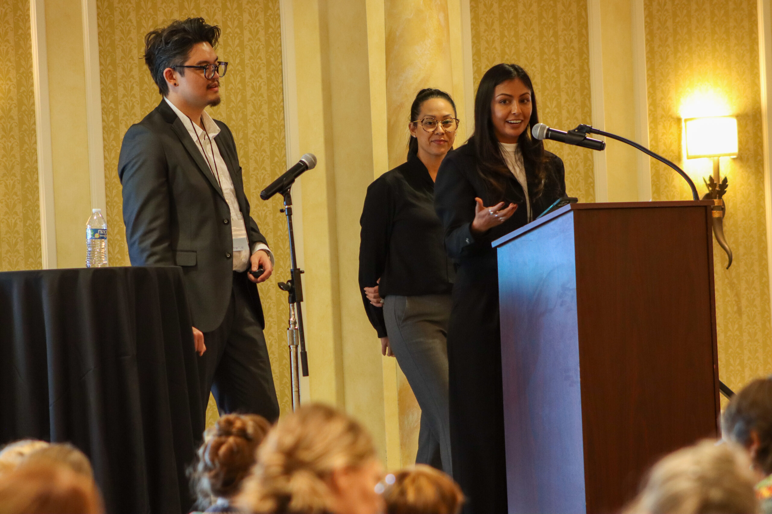 Three people stand on stage.