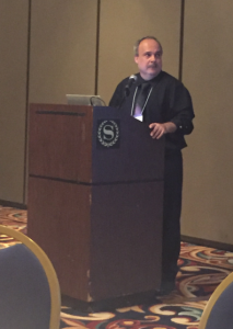 librarian Bill Mongelli standing at a podium and speaking